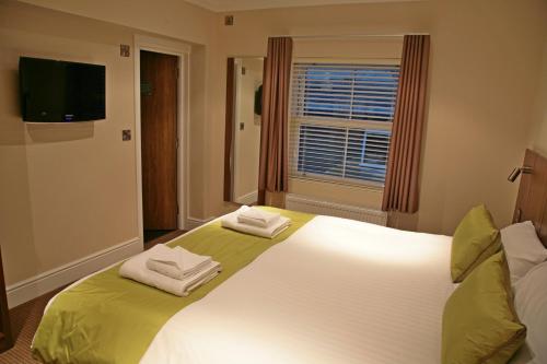 Buxted巴克斯泰德旅馆的卧室配有带毛巾的大型白色床