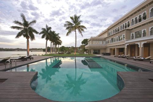 乌代浦拉肯德酒店的一座棕榈树建筑旁边的大型游泳池