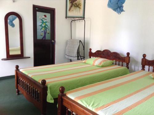 汉班托塔Lagoon Inn的一间卧室配有两张床和镜子
