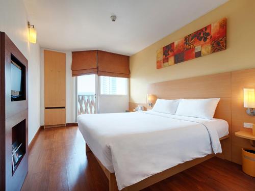 芭堤雅市中心芭提雅宜必思酒店的卧室配有一张白色大床和电视。