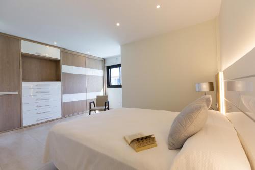 阿吉内金海滩Arguineguín Bay Apartments的卧室配有一张白色大床和一把椅子