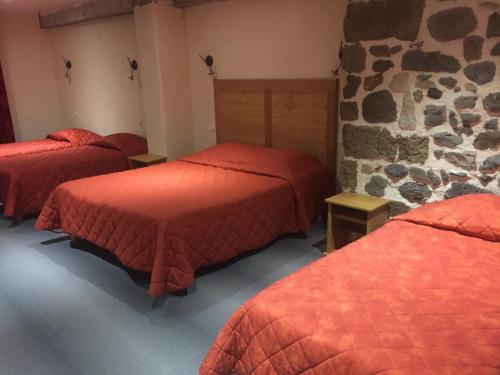 勒布伊比尔波克酒店的一间设有三张床和石墙的房间