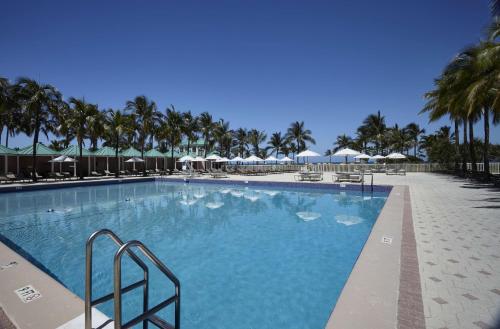 迈阿密海滩海景酒店的一座棕榈树和遮阳伞的大型游泳池