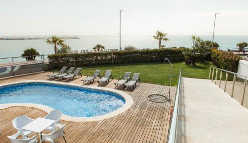 安波拉火烈鸟酒店的一个带椅子的游泳池,背景是大海