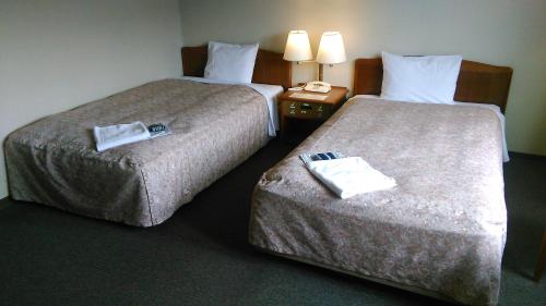 Echizen武生皇冠山酒店的两间相邻的床铺位于酒店客房内