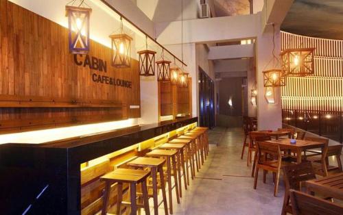 雅加达卡宾酒店的餐厅设有木桌和椅子及灯