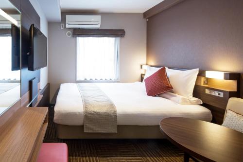东京MYSTAYS 五反田酒店的酒店客房设有一张大床和一张桌子。