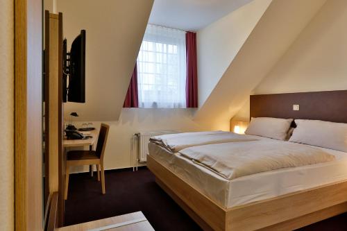 卡门Hotel Stadt Kamen的一间卧室配有一张床、一张书桌和一个窗户。