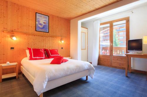 谷雪维尔Hotel Club Blanche Neige的一间卧室配有一张带红色枕头的床和电视。