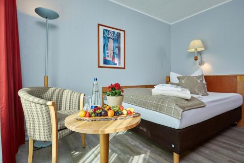 加尔米施-帕滕基兴Hotel Königshof的酒店客房,配有床和一张带水果的桌子