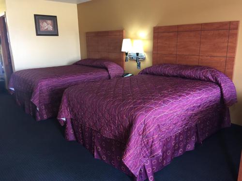 PearsallRoyal Inn Pearsall的紫色毯子,酒店客房内的两张床