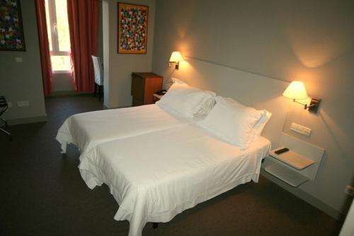 塞哥维亚波萨达牧场酒店的一间卧室配有一张带两盏灯的大型白色床。