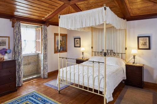 塞洛里库迪巴什图Casa de Canedo的一间卧室设有天蓬床和木制天花板