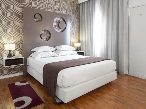 马普托马普托蒂沃里酒店的卧室配有一张白色大床和两面镜子