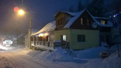 阿尔布勒茨缇策维基泽尔斯基弛霍拉次Apartmánek u Špičáku的雪覆盖在晚上的房屋,有街灯