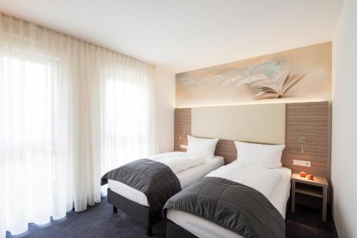 莱比锡莱比锡图书酒店的配有2张床的白色墙壁和窗户客房