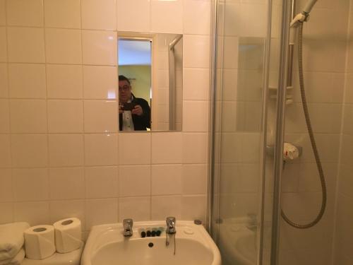 泰晤士河畔里士满公爵头酒店的一个人拍着一个浴室的照片,浴室里设有水槽和淋浴