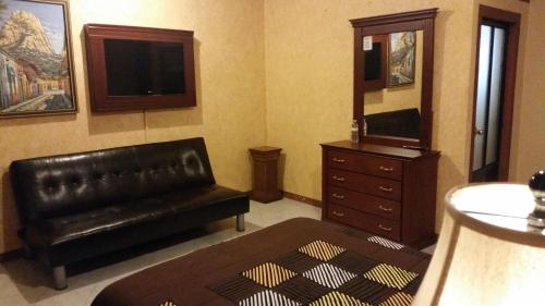 贝纳尔Hotel Villa Bernal的客厅配有黑色真皮沙发和梳妆台