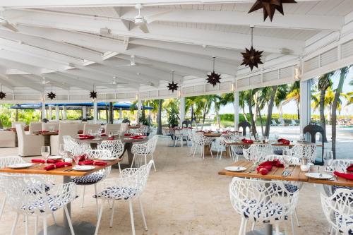 格雷斯湾Blue Haven Resort- All Inclusive的餐厅拥有白色的桌椅和棕榈树