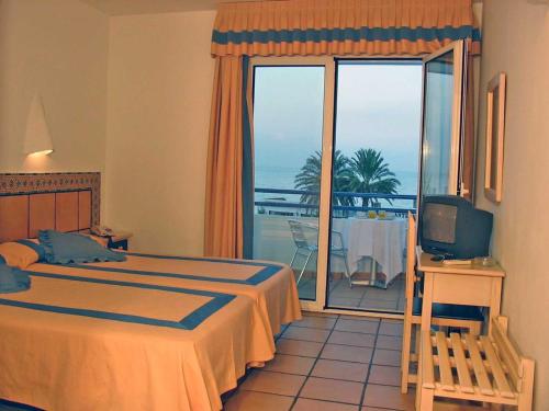 莫哈卡尔Virgen del Mar Holidays的一间卧室配有一张床、一台电视和一个阳台