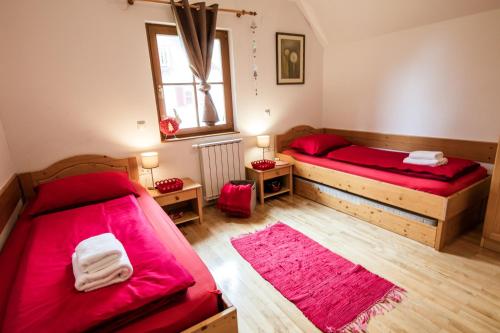 霍茨科波霍尔耶Apartments Mariborsko Pohorje的配有红色床单和木地板的客房内的两张床