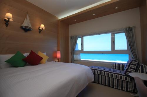 Dahan七星潭渡假饭店的一间卧室设有一张床和一个海景窗户