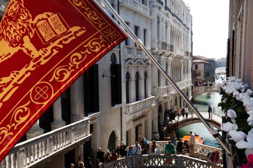 威尼斯多纳宫酒店的阳台设有国旗,享有桥梁美景。