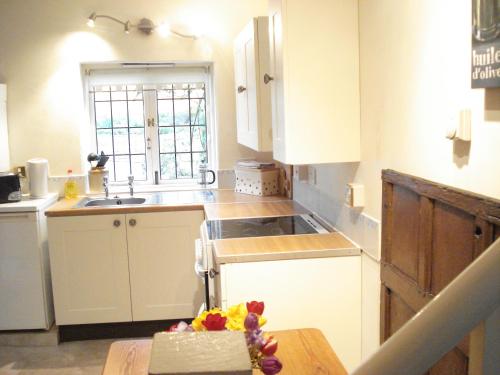 贝德福德Fosbroke Cottage的厨房配有白色橱柜、水槽和桌子