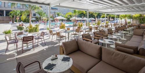 塞维利亚布雷罗斯美利亚酒店的一间带沙发和桌子的餐厅以及一个游泳池
