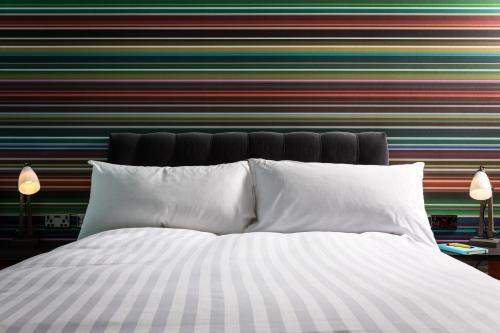 泰恩河畔纽卡斯尔纽卡斯尔乡村酒店的条纹墙前的一张带白色枕头的床
