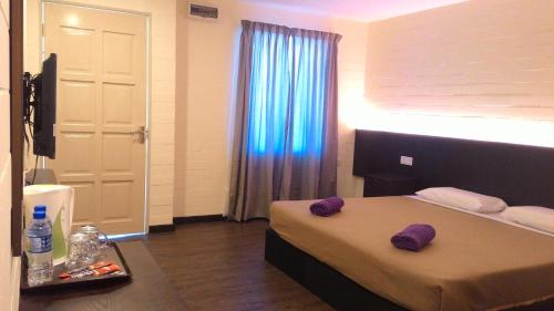 珍南海滩萨伊哈宾馆的一间卧室配有一张带紫色毛巾的床