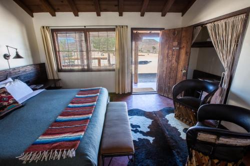 Pioneertown先锋镇汽车旅馆的卧室配有床、椅子和窗户。