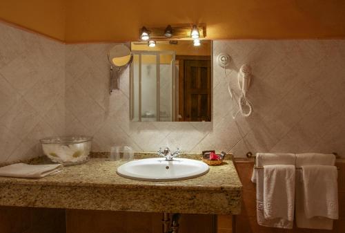 纳瓦斯-德尔马德罗尼奥Casa Rural La Chimenea的浴室配有盥洗盆、镜子和毛巾