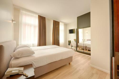 布鲁日普耶酒店的白色卧室配有床和镜子