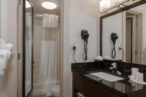 波士顿波士顿华美达酒店的一间带水槽和淋浴的浴室以及一部电话