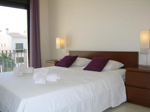 圣哈维耶尔Roda Golf Resort 8007 - Resort Choice的卧室配有一张带紫色枕头的大型白色床。