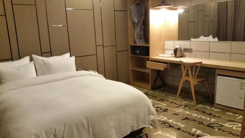 首尔阔博斯酒店的一间酒店客房,配有一张白色的床和一张书桌