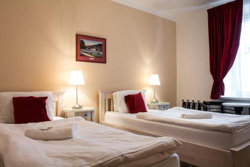 拉贝河畔乌斯季皮沃瓦纳莱切酒店的配有红色窗帘的酒店客房的两张床