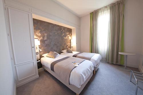 克莱蒙费朗Hôtel Albert Elisabeth Gare SNCF的酒店客房设有两张床和窗户。