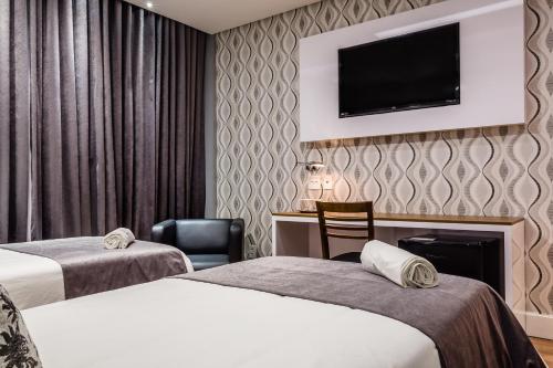 圣若昂迪梅里蒂里约热内卢时尚酒店的酒店客房设有两张床和一台墙上的电视。