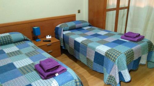 洛格罗尼奥卡尔菲来德二世宾馆的两张位于酒店客房的床,配有紫色毛巾