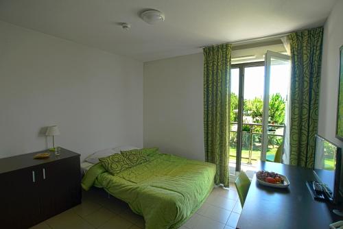 蒙法维KOSY Appart'Hôtels - Campus Del Sol Esplanade的一间带绿色床的卧室和一个阳台