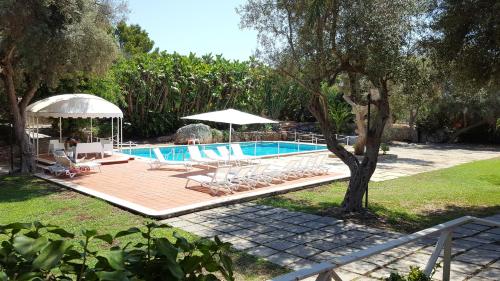 锡拉库扎Resort Villa Isola B&B的庭院内带椅子和遮阳伞的游泳池