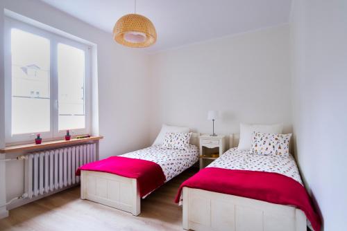 奥尔什丁Apartament Na Staromiejskiej的白色客房的两张床,设有窗户