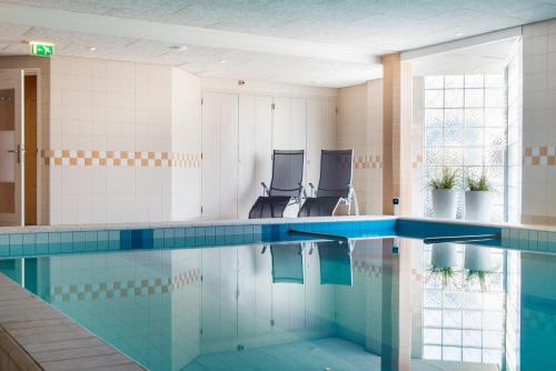 奥门Paping Hotel & Spa - Rest Vonck by Flow的大楼内一个带两把椅子的游泳池