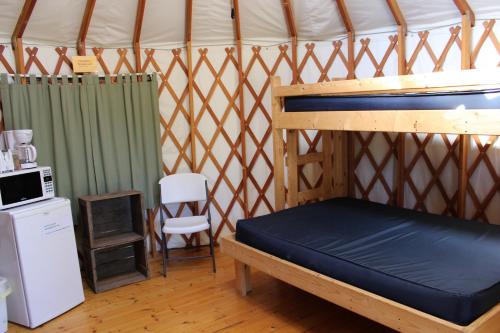斯特金贝Tranquil Timbers Yurt 3的蒙古包内的一张床位,配有冰箱和椅子