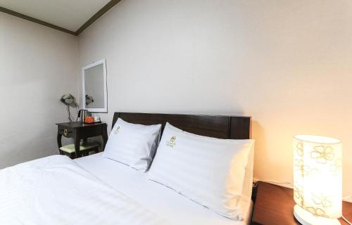大田水晶住宅酒店的一间卧室配有一张带白色床单和一盏灯的床。