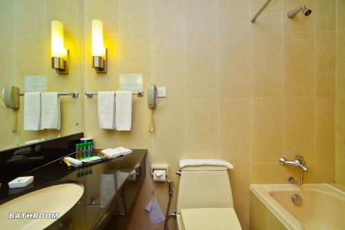 米里美里王朝酒店的浴室配有盥洗盆、卫生间和浴缸。