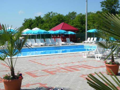 罗曼Motel Imperial的游泳池配有椅子、蓝伞和椅子