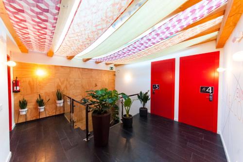塞哥维亚El Mirador Del Alcazar的走廊上设有红色的门和盆栽植物